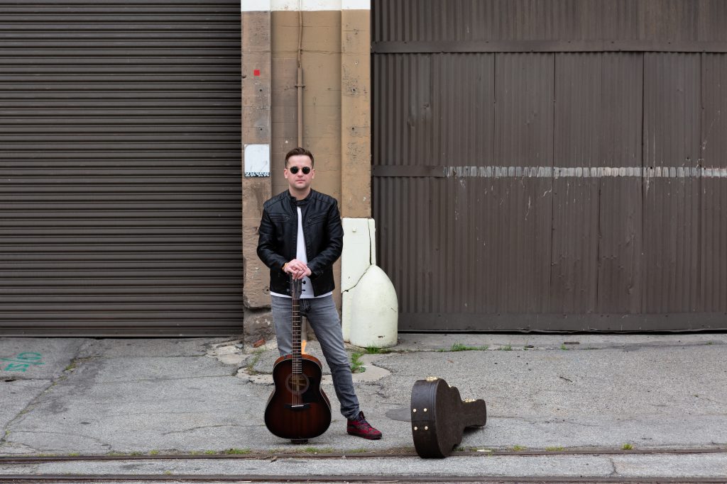 Tyler Boone with a guitar and case.
