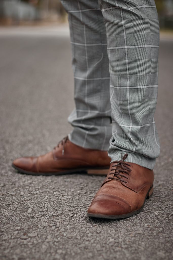 A man wearing brown shoes with grey trousers.