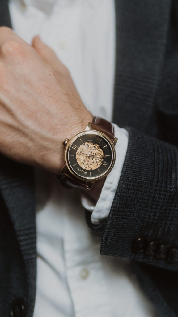 A man wearing a gold and brown wrist watch.