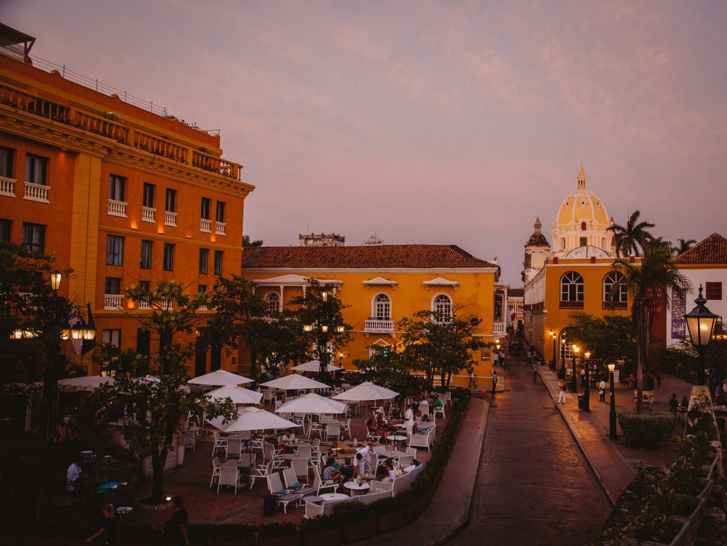 A European style restaurant with white parasails against the backdrop of yellow buildings and domes.