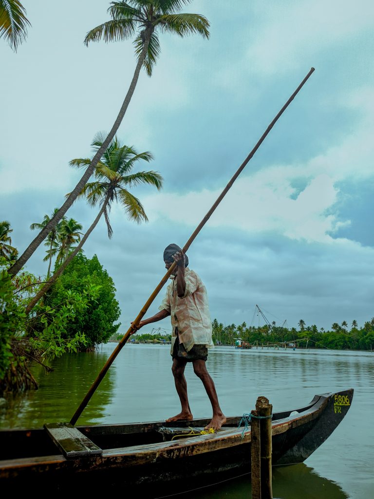 A man using a poll to push a boat in Kerala's backwaters.
