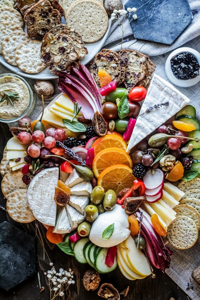 Cheeses fruits and vegetables on a platter.