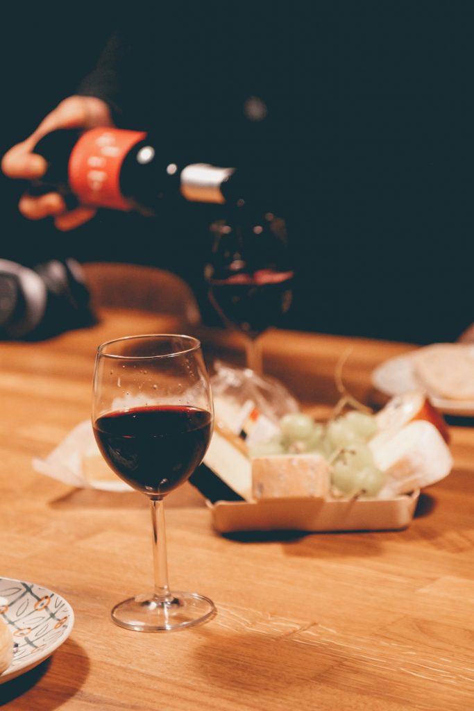 A glass of wine with some cheese.