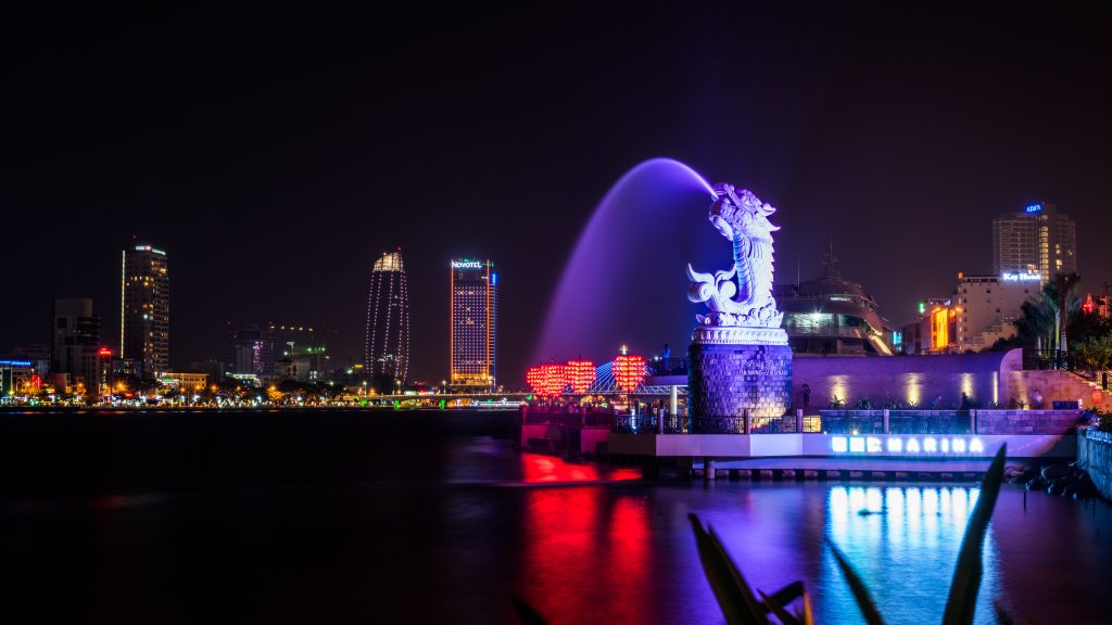 Da Nang in Central Vietnam. A dragon fountain spraying water into the river with skyscrappers in the background.