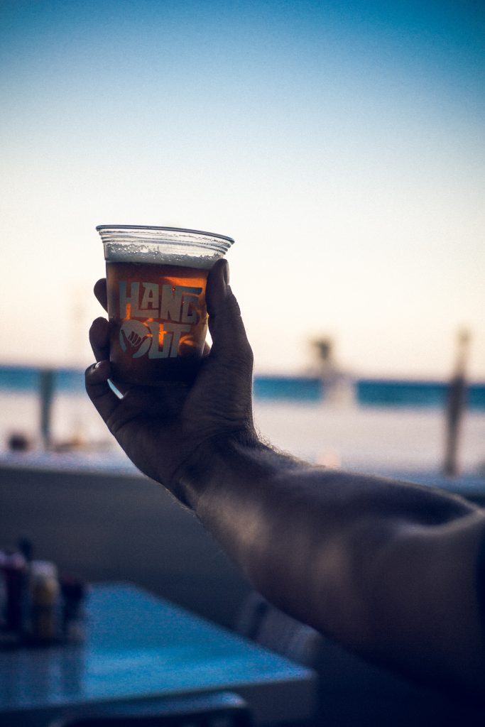 A man holding a plastic cup of beer which says 'Hangout' on it.