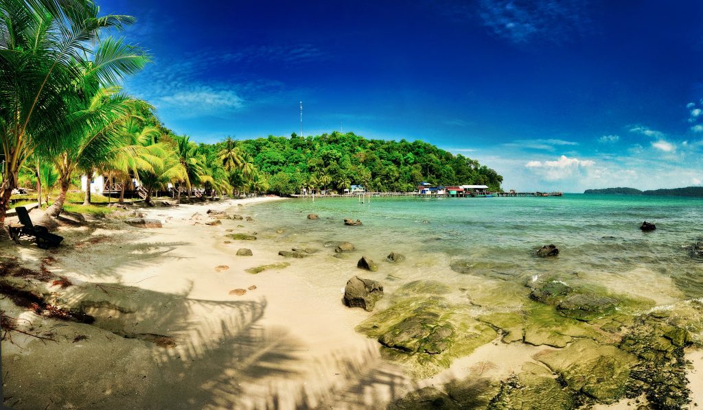 Koh Rong in Southern Cambodia, green vegetation surrounding a beach.