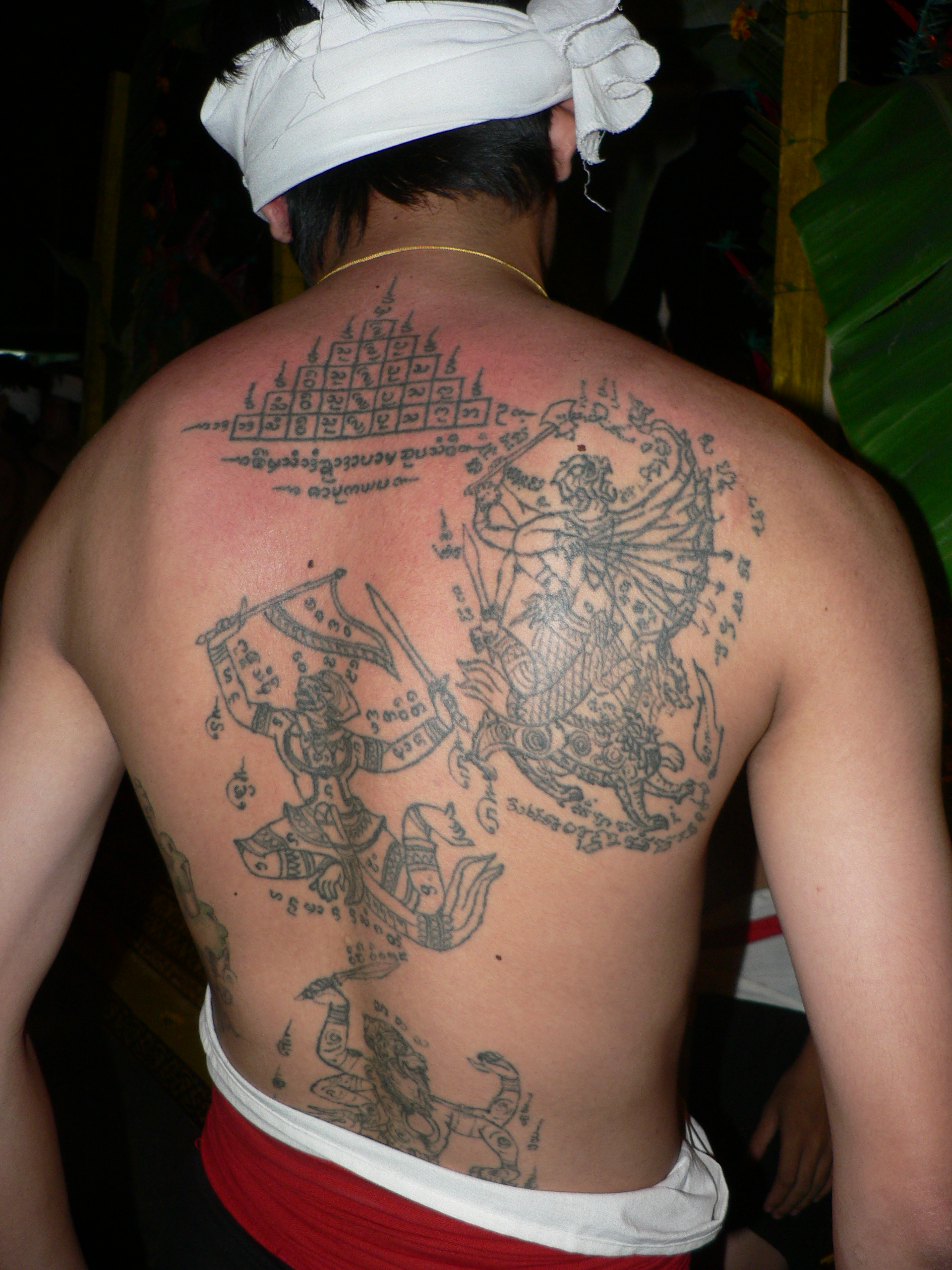A finished sak yant tattoo design of yantra figures and script covering a man's back